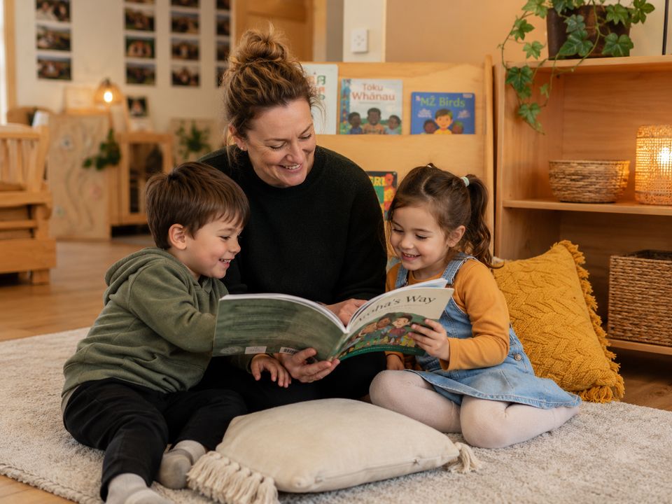 Teacher reading with children in a warm literacy corner