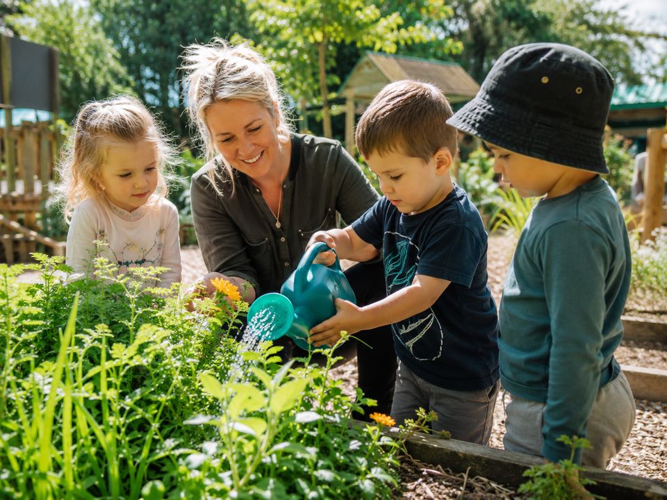 Children learning outdoors in the garden with a teacher